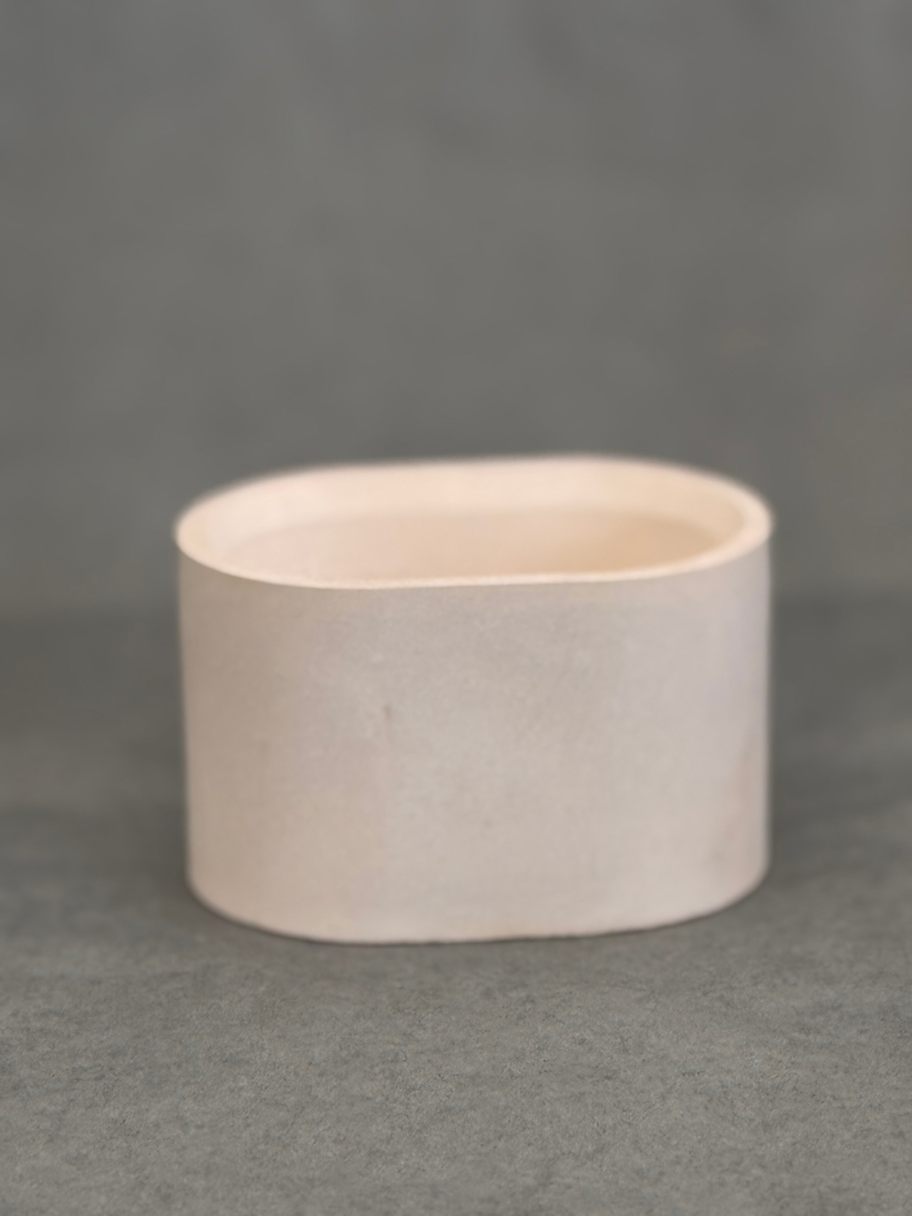 Beige concrete oval bowl on a grey background