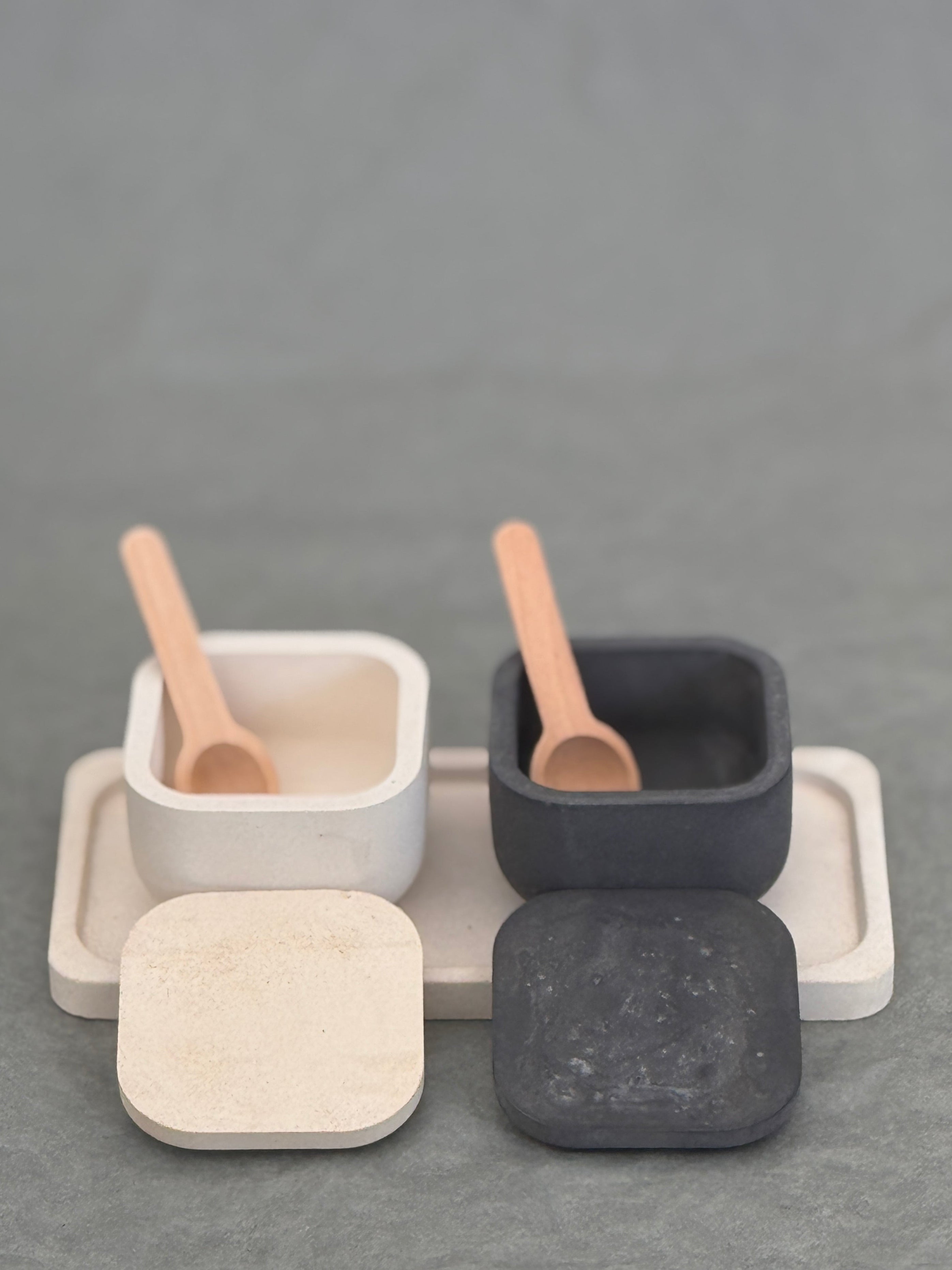 Set of square containers with lids and wooden spoons on a gray background
